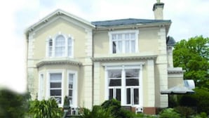A two-story building with a symmetrical facade, large windows, and a central entrance. - Ansteys Lea Guest House (Torquay)