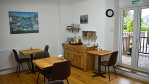 A dining area with a wooden table and chairs, a kitchen counter with various items, and a view through a glass door. - Acorn Lodge (Torquay)