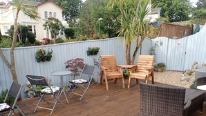 A wooden deck with outdoor furniture, including chairs and a table. - Acorn Lodge (Torquay)