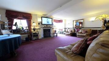 Una sala de estar con chimenea, televisor y sofá.