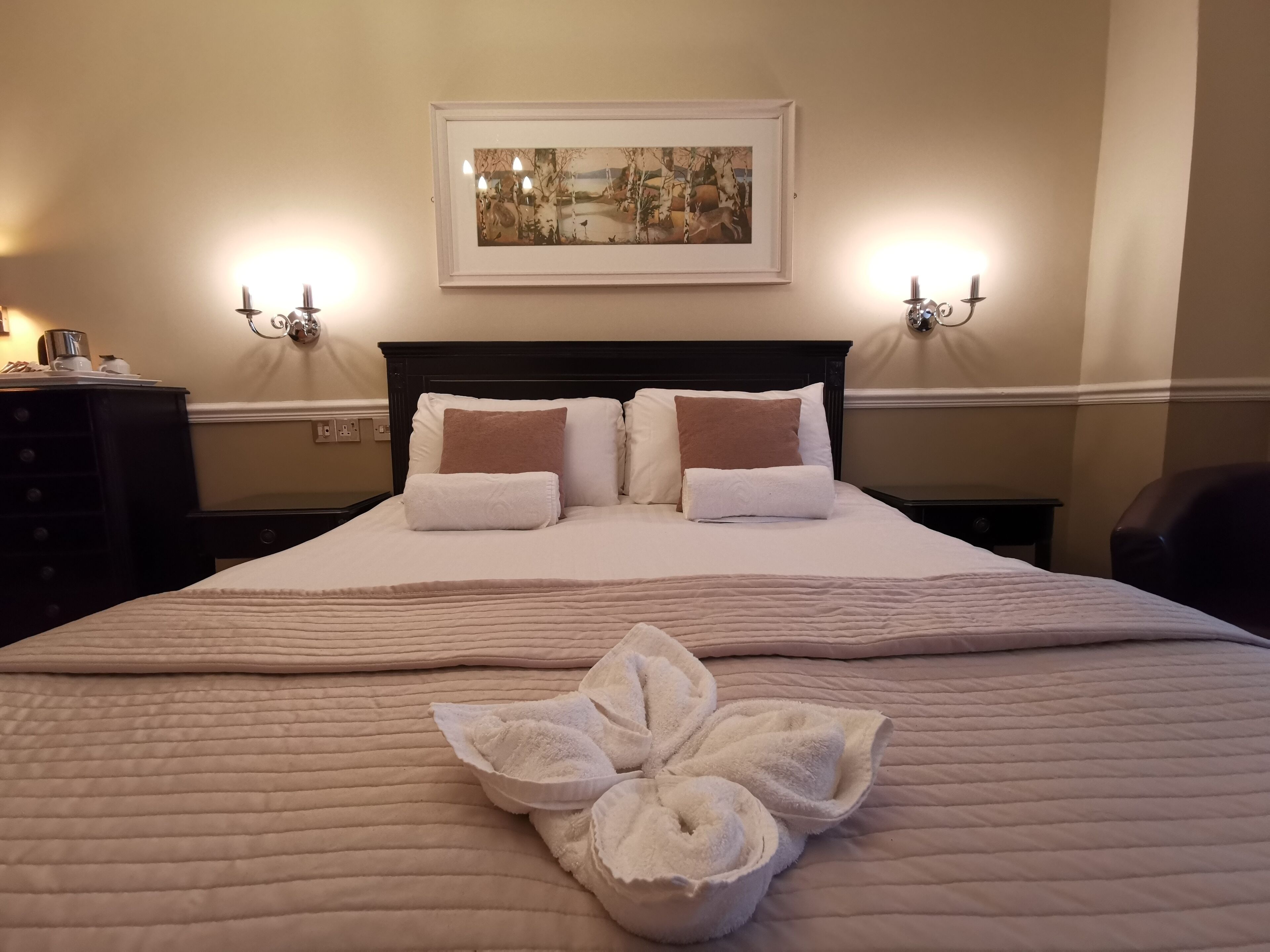 A neatly made bed with a quilted bedspread, two pillows, and a decorative towel arrangement.