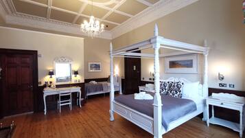 A four-poster bed with a canopy, a desk with a chair, a dresser, and a mirror.