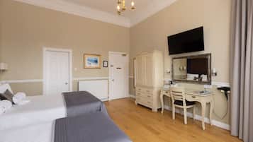 Een hotelkamer met twee bedden, een bureau, een dressoir, een televisie en een spiegel.