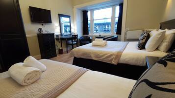 A hotel room with two beds, a desk, a chair, a television, and a window with a view.