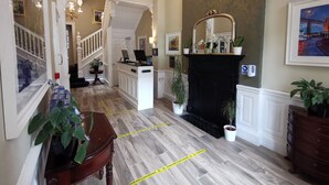 Un hall de hotel con una recepción, una chimenea y una escalera.