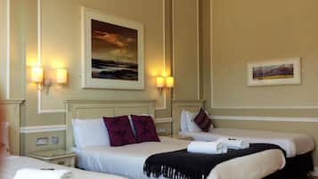 A hotel room with two beds, a painting on the wall, and two wall-mounted lamps.
