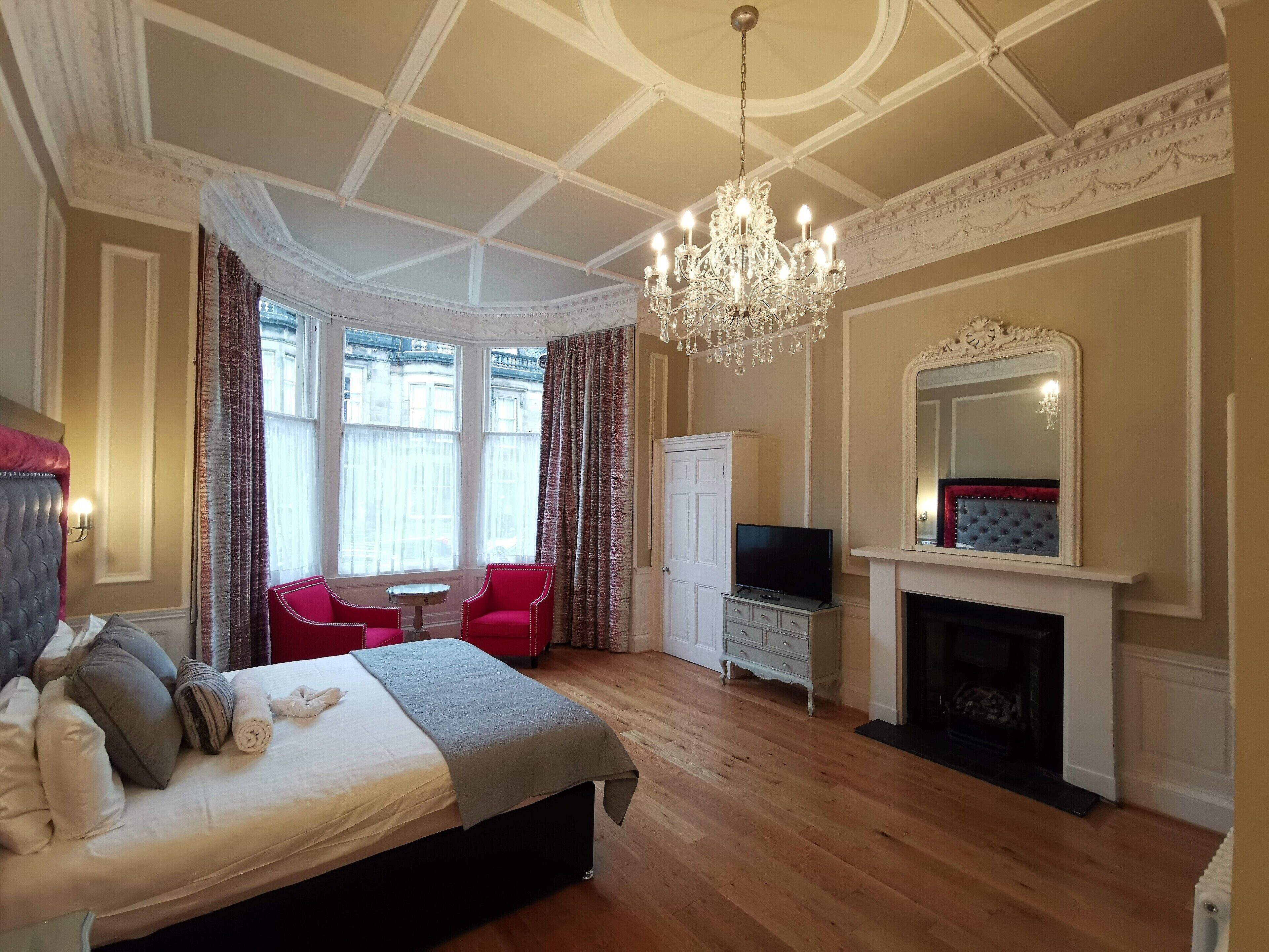 Un dormitorio con cama, televisión, chimenea y candelabro.