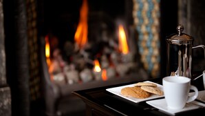 A fireplace with visible flames, a coffee pot, and cookies on a tray. - The Grafton (Harrogate)