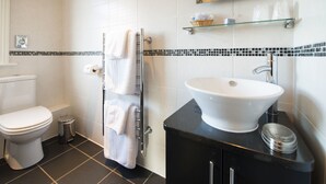 A modern bathroom with a white toilet, a black sink, and a glass shelf above the sink. - The Grafton (Harrogate)