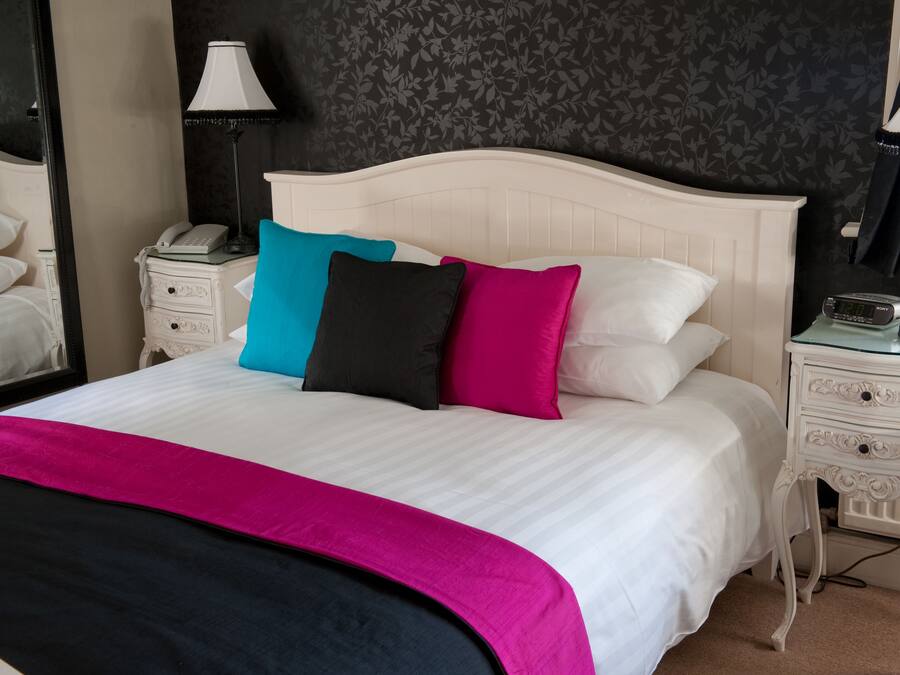 A neatly made bed with a white headboard, a bedside table with a lamp, and a telephone.