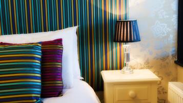 Un lit avec des oreillers à rayures, une lampe de chevet et un rideau à rayures dans une chambre d’hôtel.