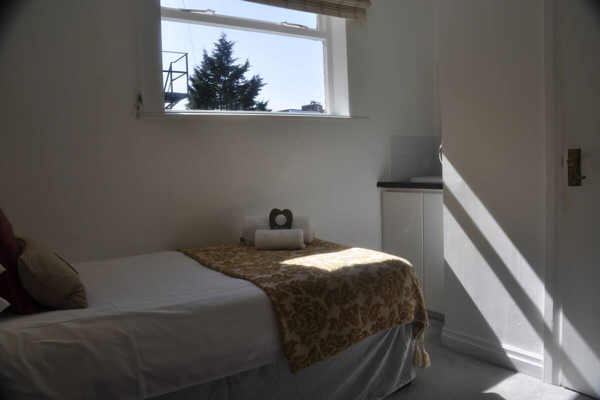 Un dormitorio con cama, ventana, mesita de noche y armario.