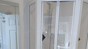 A modern bathroom with a glass-enclosed shower, a white sink, and a mirror above the sink. - Arden House (Harrogate)