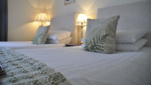 A hotel room with two beds, each with a pillow and a bedside lamp. - Arden House (Harrogate)