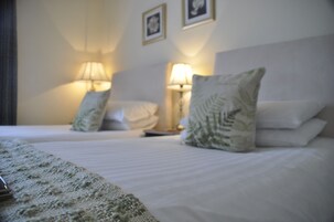 A hotel room with two beds, each with a pillow and a bedside lamp.
