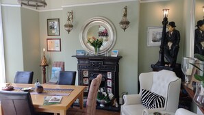 A dining area with a wooden table, chairs, and a fireplace with a mirror above it. - Arden House (Harrogate)