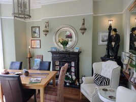 A dining area with a wooden table, chairs, and a fireplace with a mirror above it.