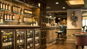 A bar area with shelves of wine bottles and a refrigerator with more bottles. There are chairs and a counter in the background. - West Park Hotel (Harrogate)