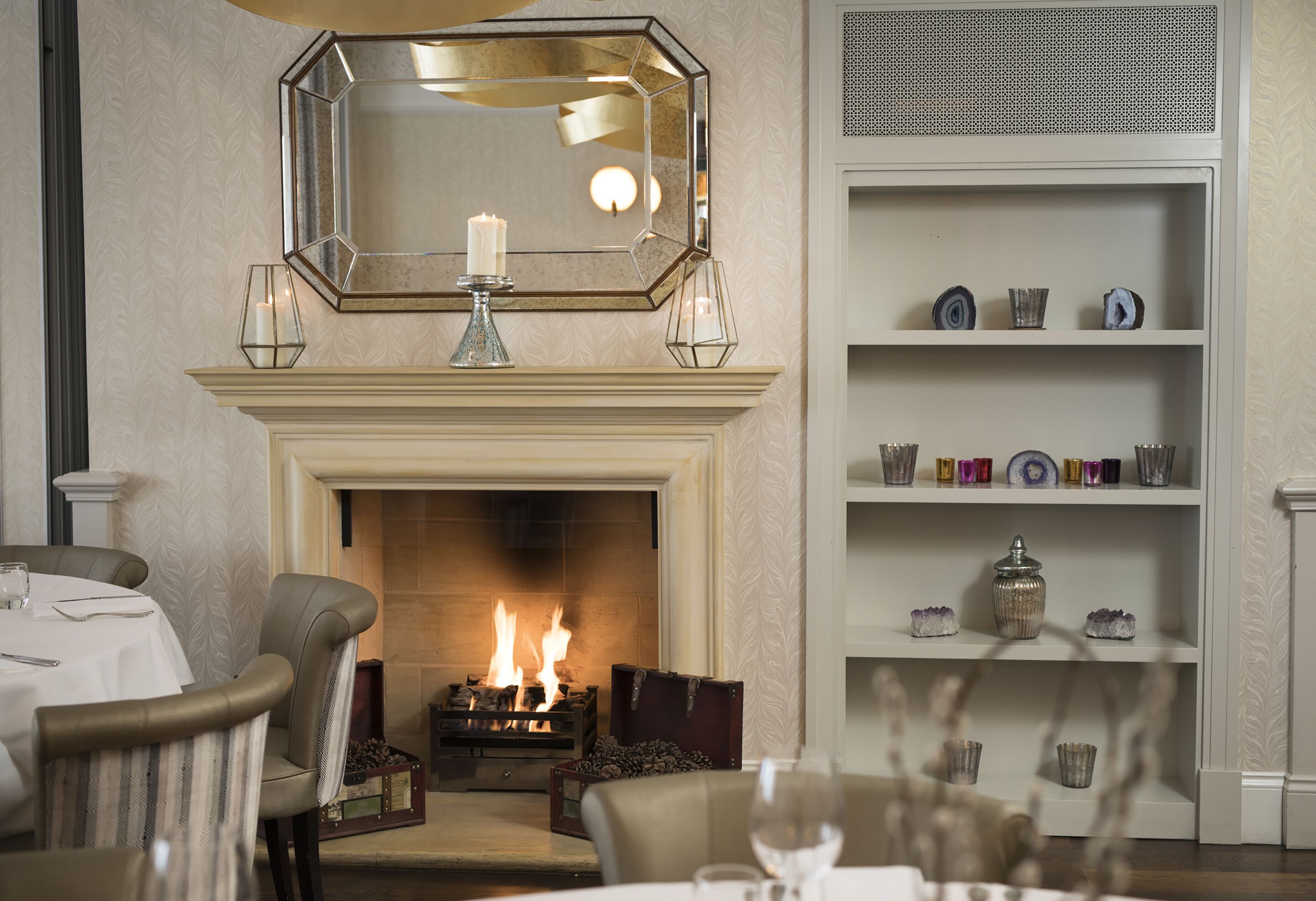 Una habitación con chimenea, espejo y estante con objetos decorativos.