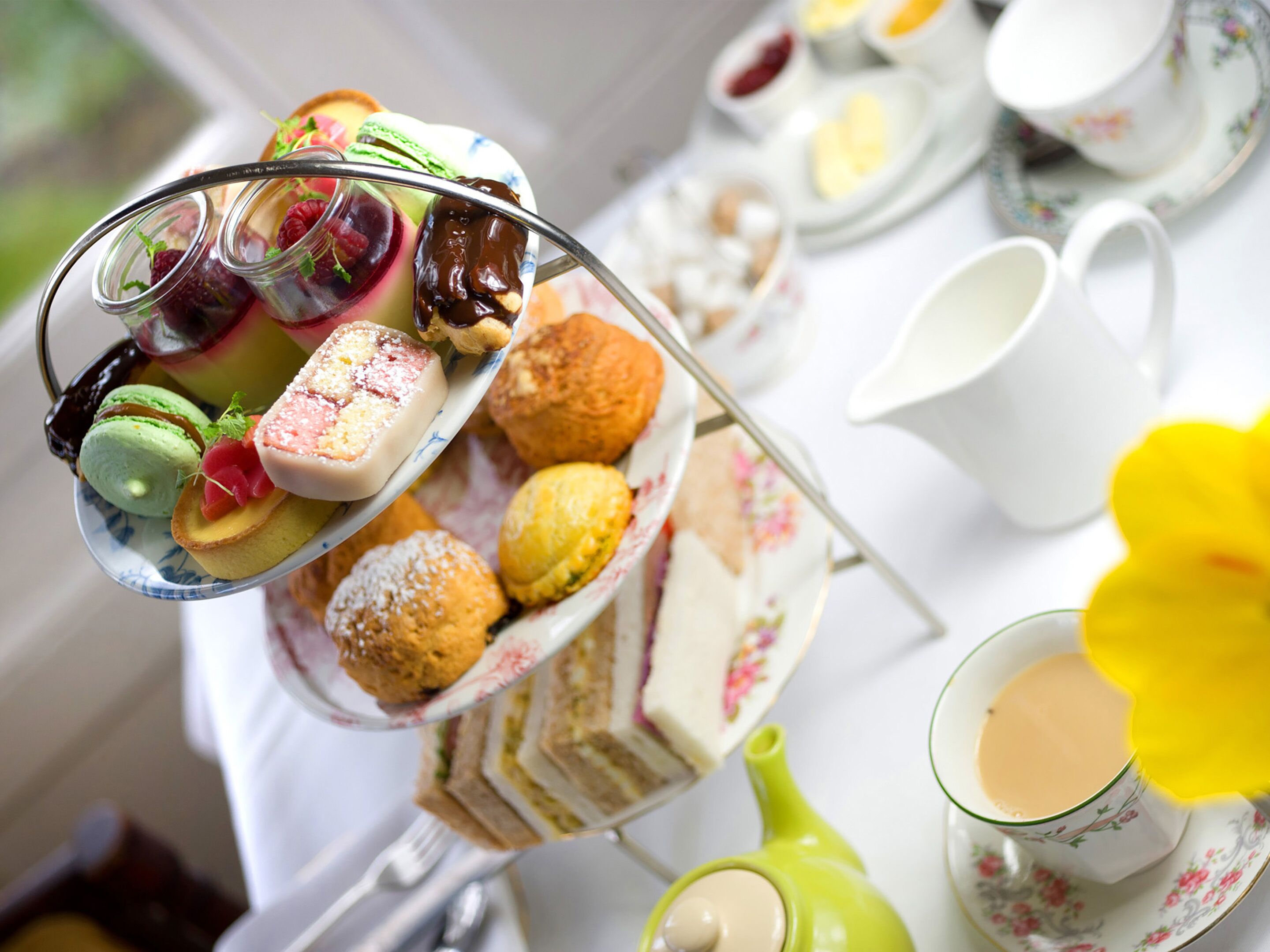 A tea service with a variety of pastries and sandwiches on a tray.