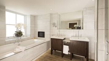 Une salle de bain moderne avec une grande baignoire, deux lavabos, un meuble-lavabo et un grand miroir.