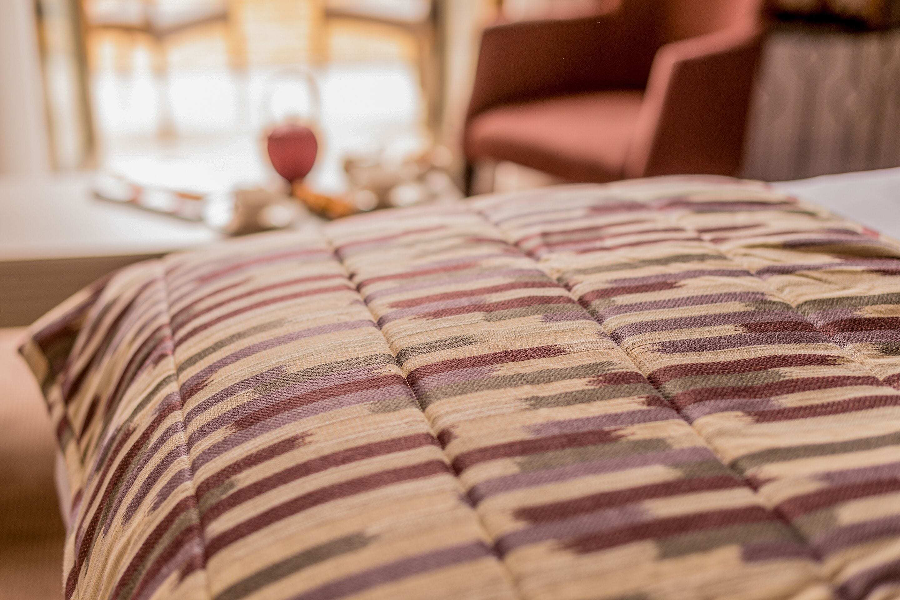 Een detail van een gestreept kussen op een bed.