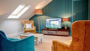 A cozy living room with a high ceiling, a television, and a comfortable seating area. - West Park Hotel (Harrogate)