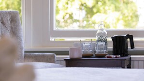 A room with a window, a small table with a coffee maker, a glass, and a white mug. - Wynnstay House (Harrogate)