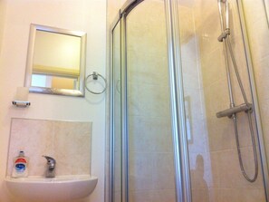 Driepersoonskamer | Badkamer | Een bad/douchecombinatie, een haardroger, handdoeken