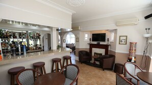 A bar area with stools and a television in the background. - The Corner House Hotel Gatwick (Horley)