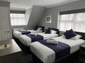 A hotel room with three beds, a desk, and a window with sheer curtains. - The Corner House Hotel Gatwick (Horley)