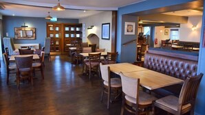 A restaurant with wooden tables and chairs, a bar area, and a seating section with a cushioned bench. - The Two Lifeboats (Sheringham)