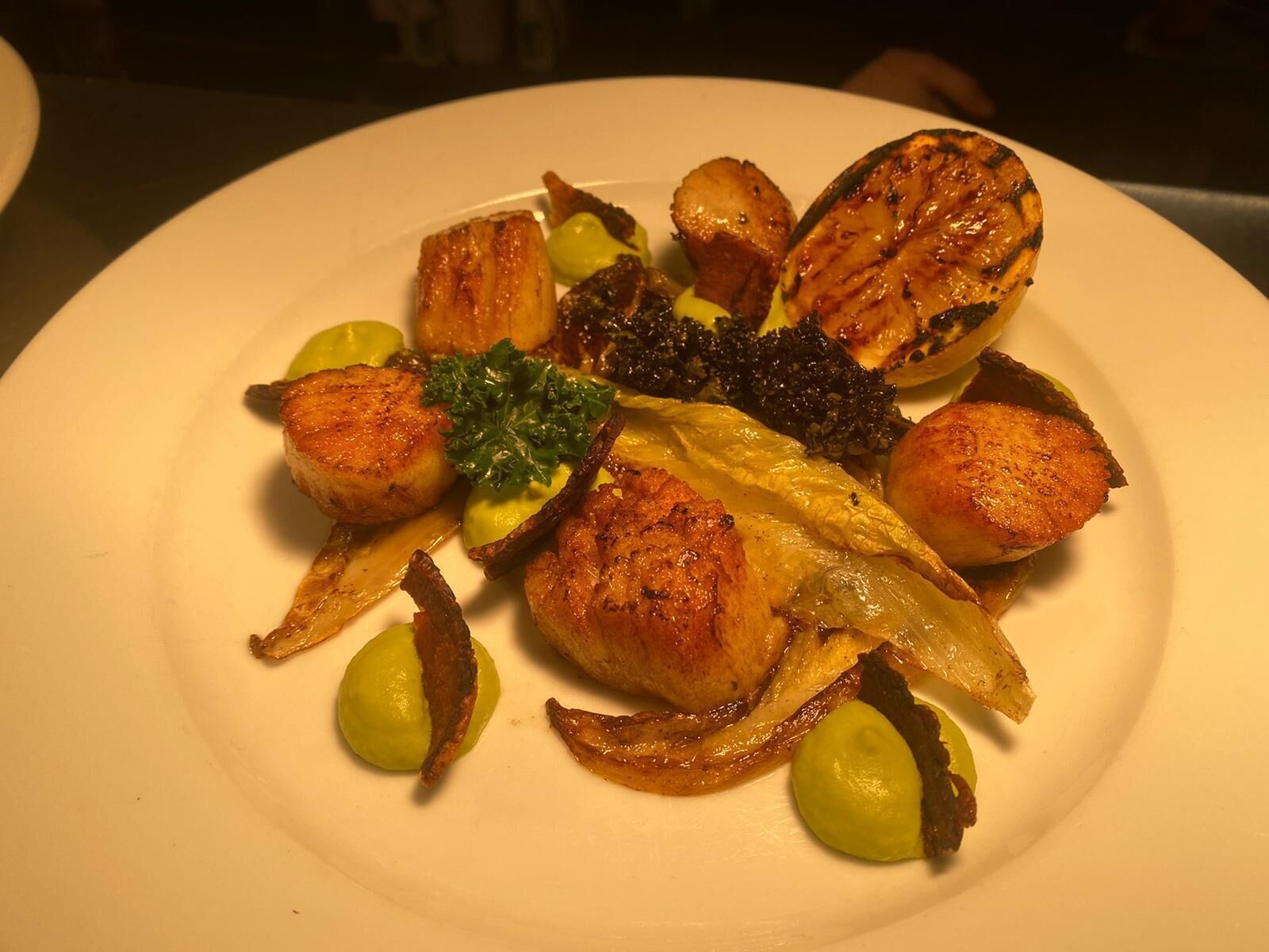 A plate of food with various items including scallops, onions, and broccoli.