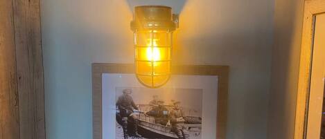 Een muur met een ingelijste historische foto, een wandlamp en een bord met tekst.