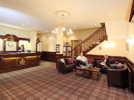 A lobby with a reception desk, a staircase, and seating areas.