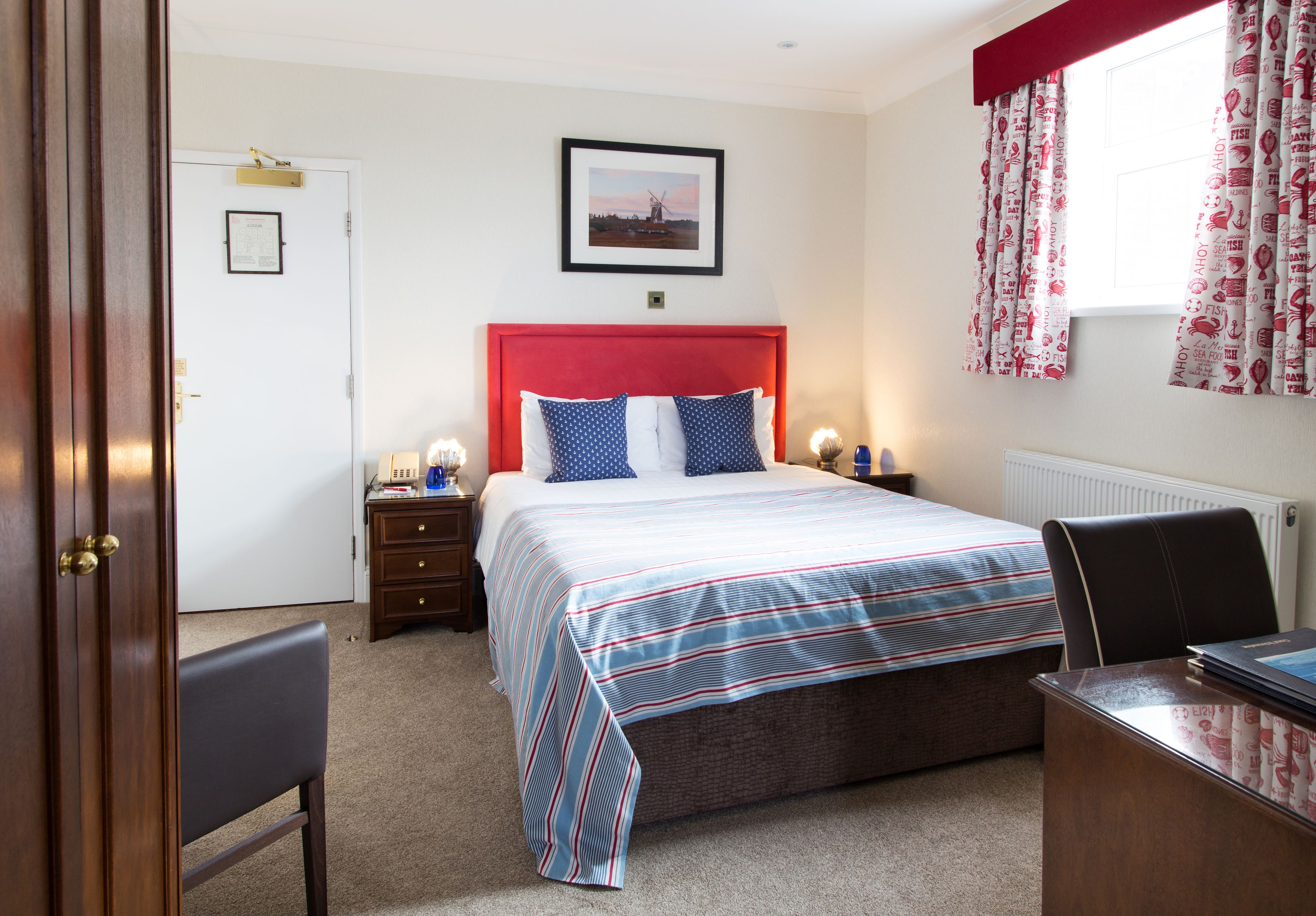 A bedroom with a bed, nightstands, a desk, and a chair.