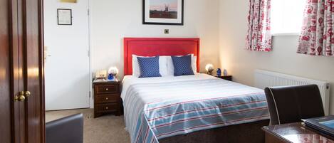 A bedroom with a bed, nightstands, a desk, and a chair.