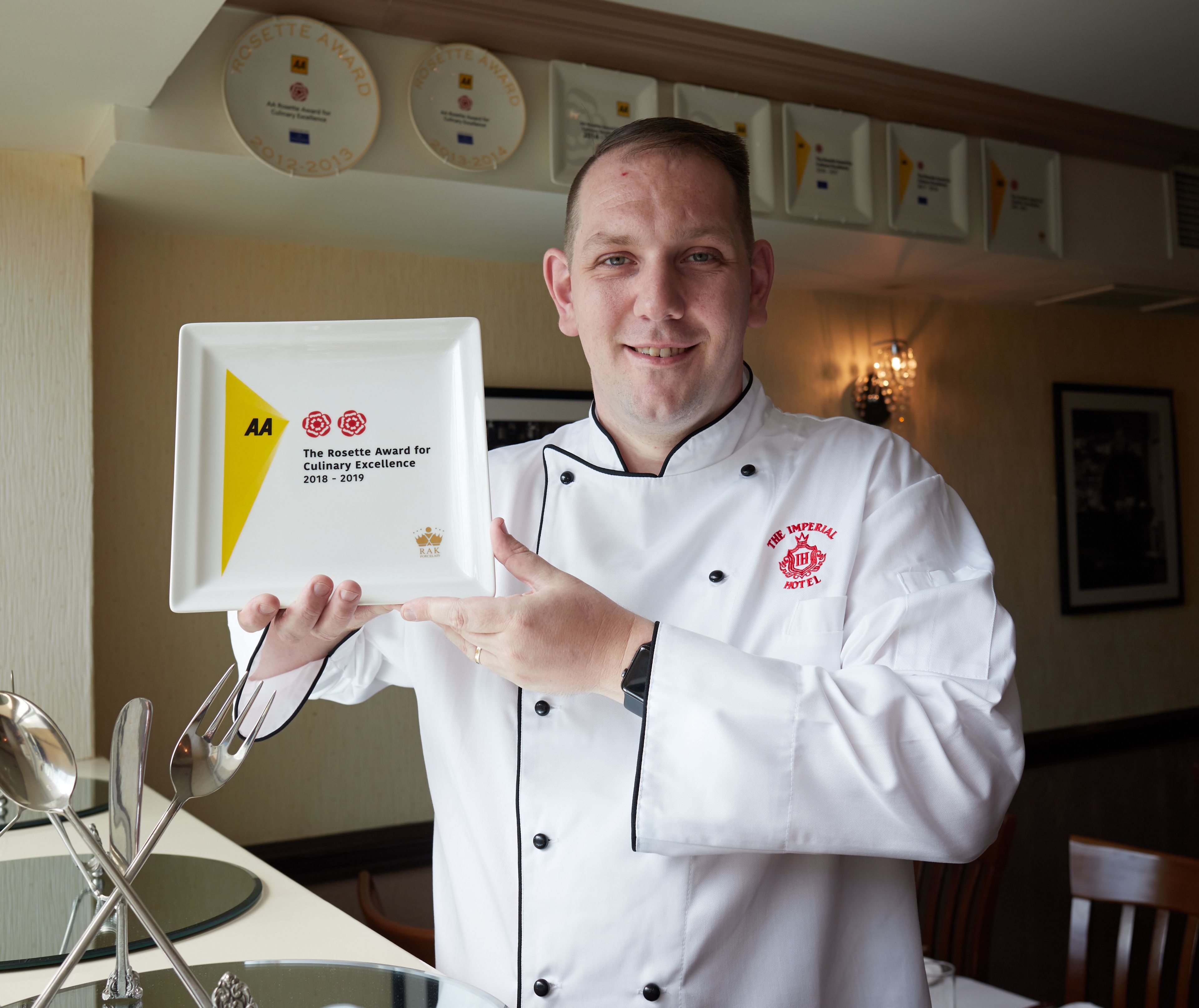 A chef holding a plaque with the text "The Rosette Award for Culinary Excellence 2018-2019".