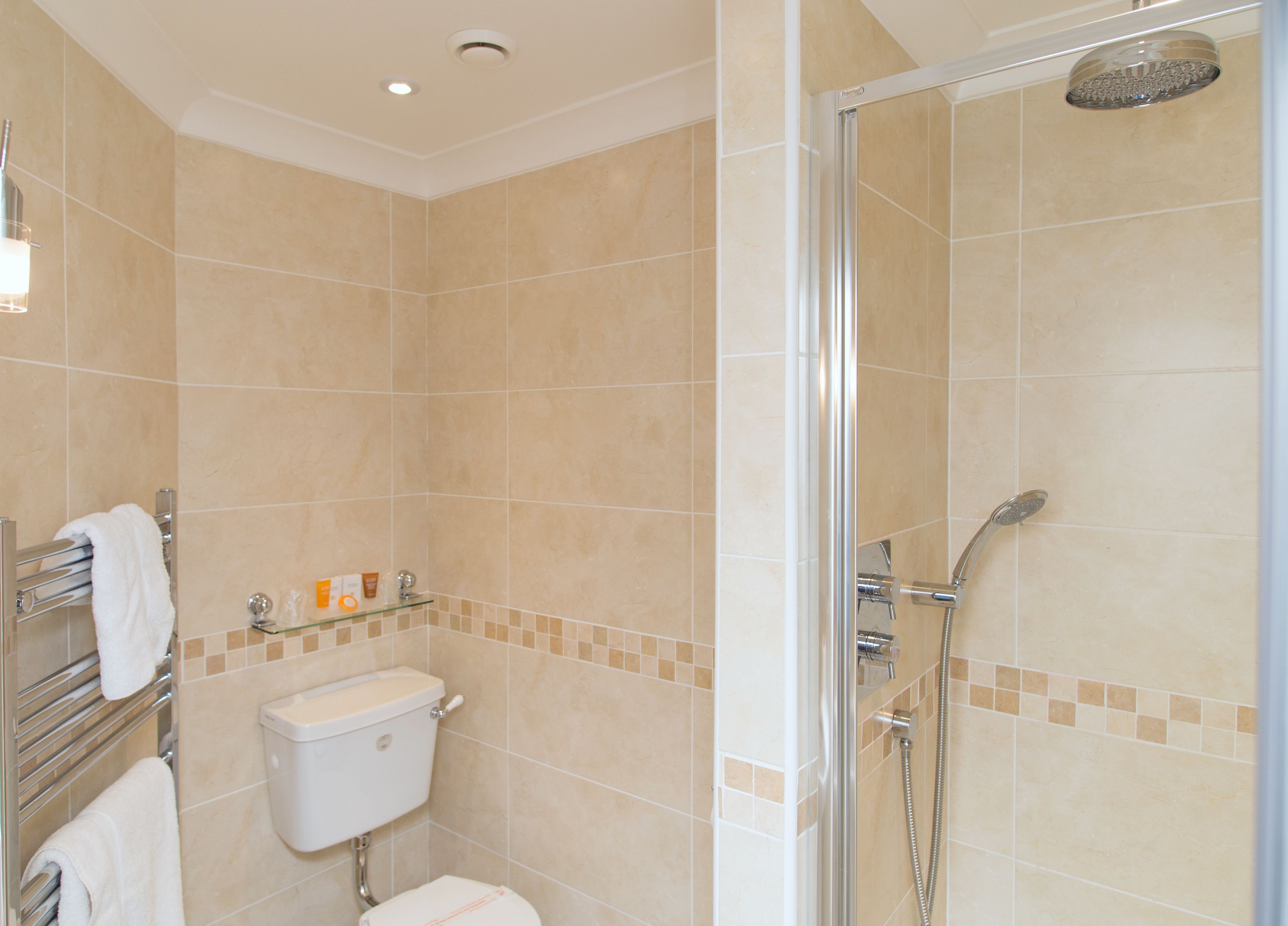 A modern bathroom with a glass-enclosed shower, a toilet, and a towel rack.