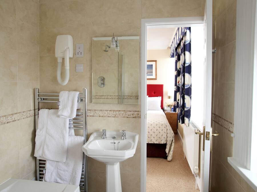 A bathroom with a sink, mirror, towel rack, and shower.