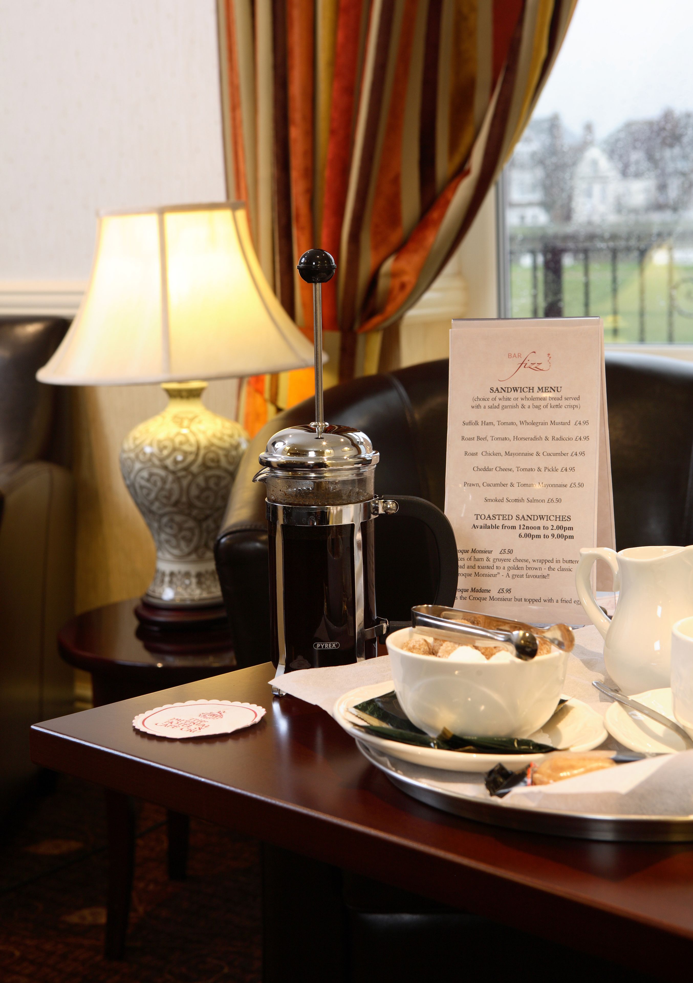 Une table de petit-déjeuner avec un menu, une cafetière, une théière et une assiette remplie de nourriture.