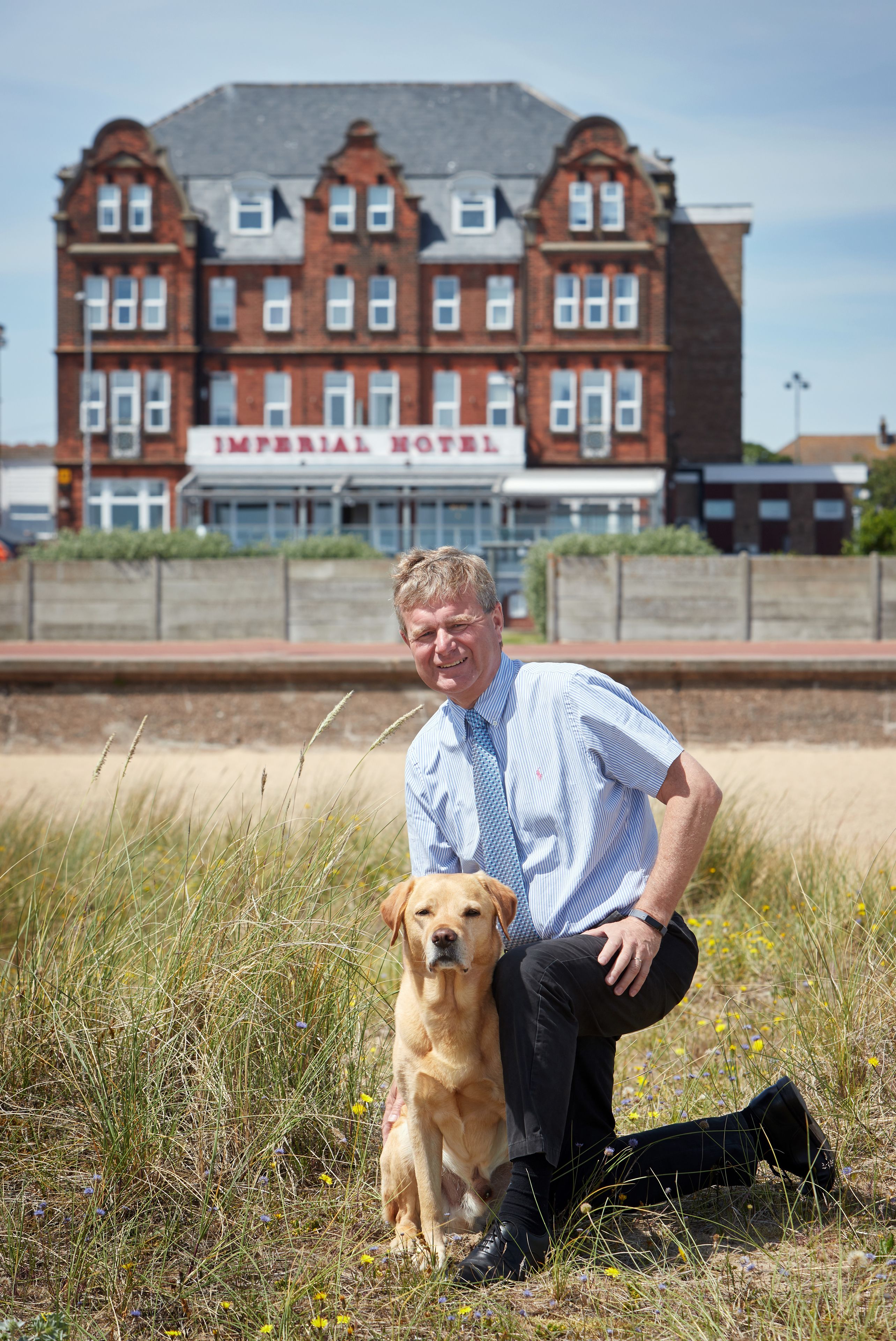 A man sitting with a dog in front of the Imperial Hotel.