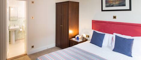 A hotel room with a bed, a nightstand, a wardrobe, and a bathroom visible through an open door.