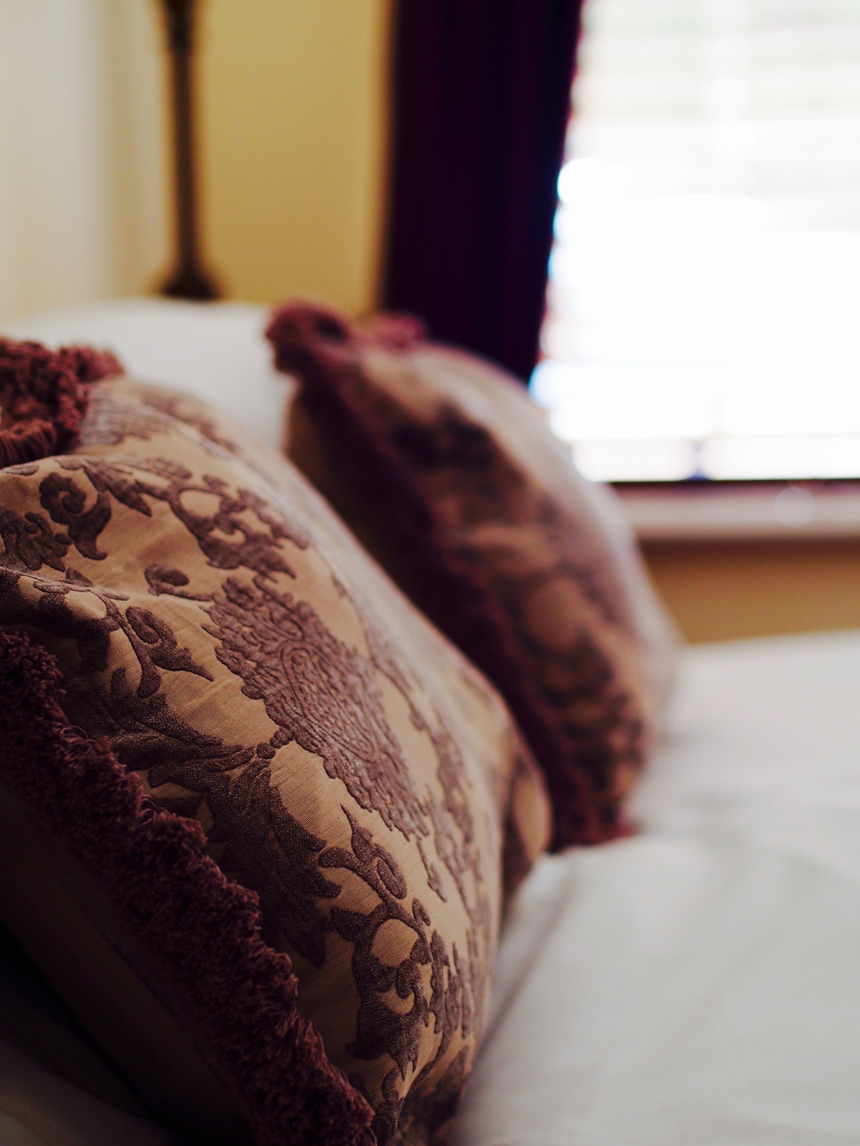 A bed with patterned pillows and a white sheet.