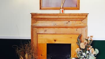 A fireplace with a framed portrait above it, flanked by two wall sconces.