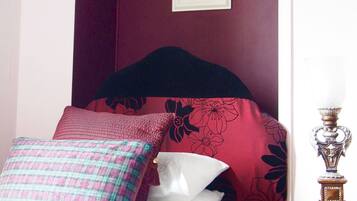 A bedroom with a bed, pillows, a nightstand, and a framed picture on the wall.
