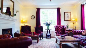 Une pièce de style traditionnel, dotée d’une cheminée, de fauteuils en cuir, d’un tapis à motifs et d’un lustre.