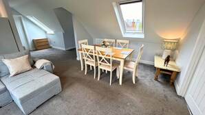 A cozy loft bedroom with a dining area, a small side table, and a window with a view. - New Forest Lodge (Salisbury)