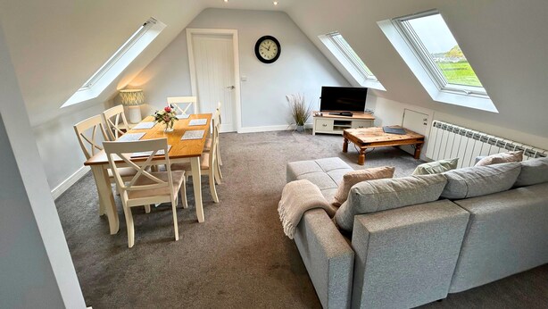 A cozy loft apartment with a dining area, a sofa, a TV, and skylights. - New Forest Lodge (Salisbury)