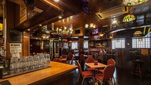 A bar area with wooden bar counters, red chairs, and various signs including a warning sign. - Scarisbrick Hotel (Southport)